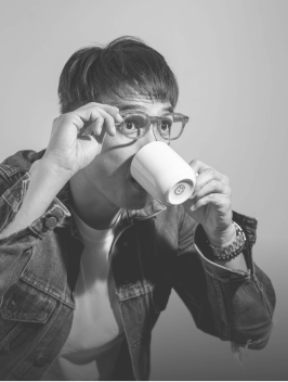 Sky holding his eyeglasses drinking from a cup