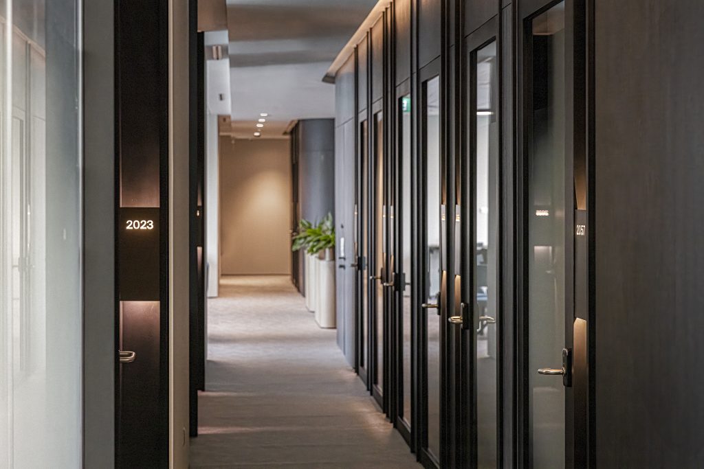 A corridor with glass doors to smaller rooms
